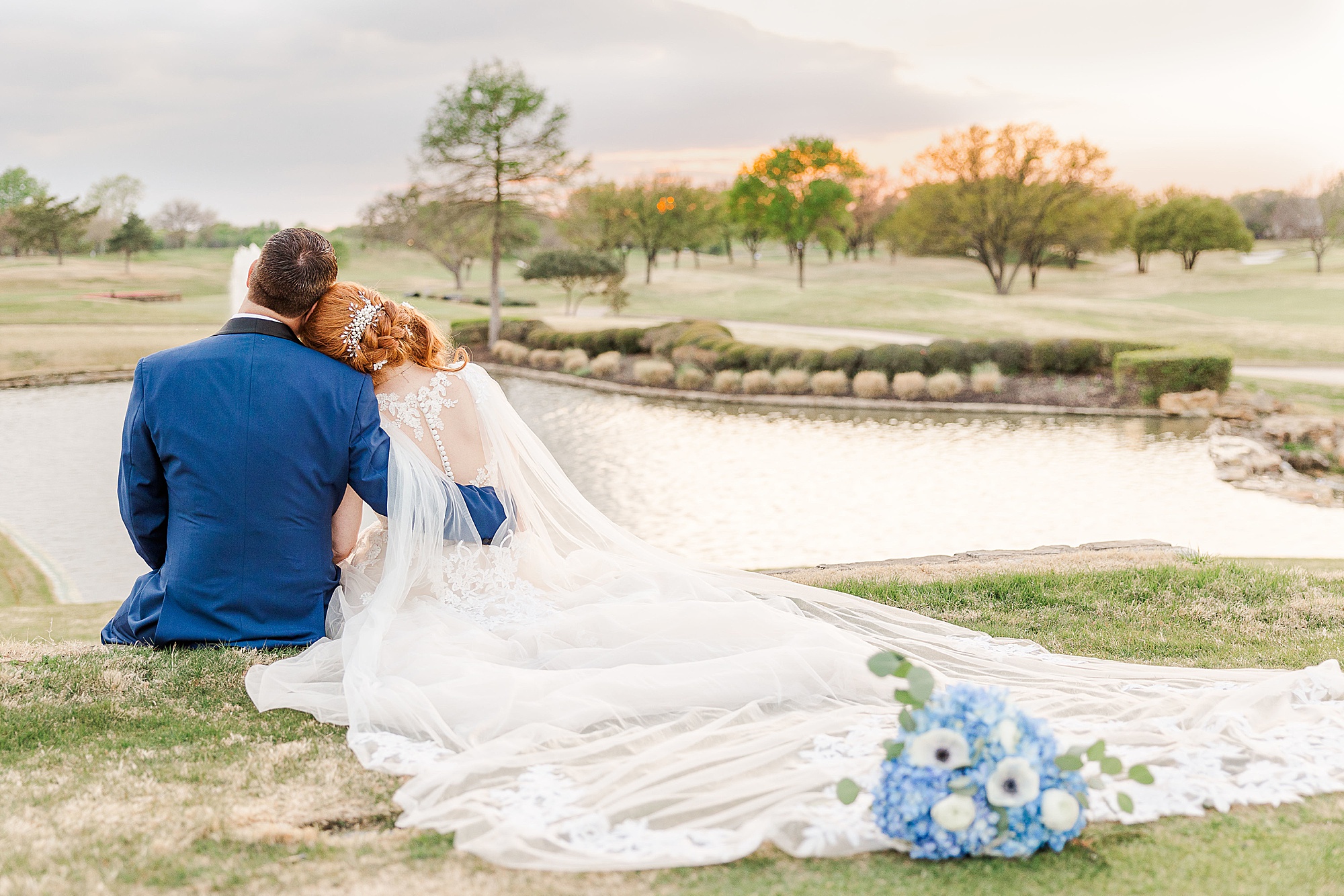 newlyweds sit by lake at Stonebriar Country Club