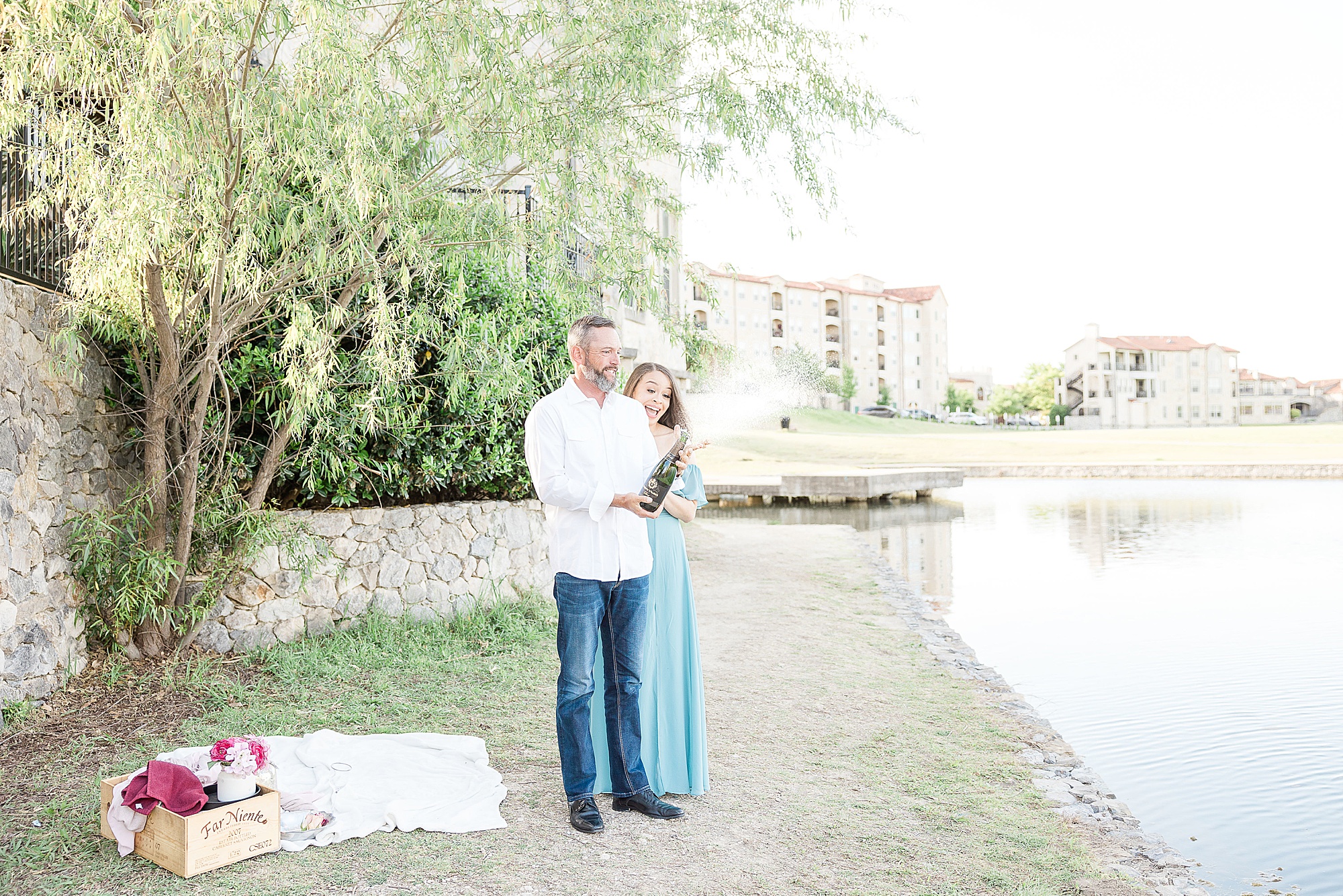 bride and groom pop champagne during Adriatica Village engagement photos 