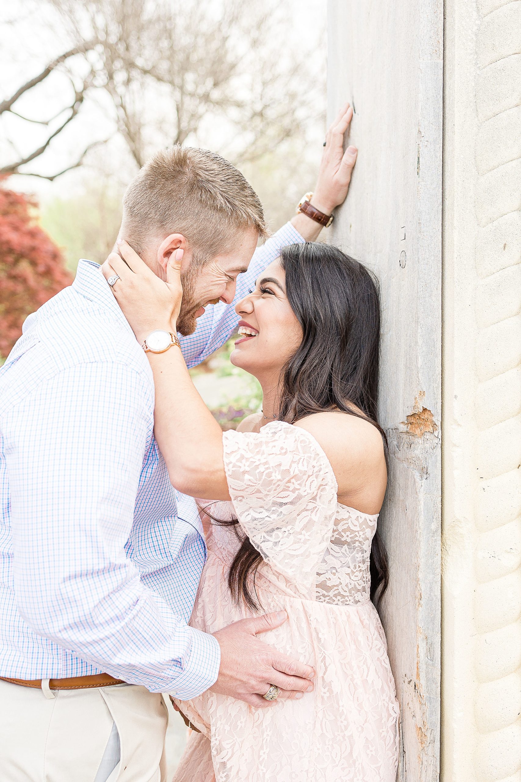 woman holds husband's cheek during Dallas Arboretum maternity session 