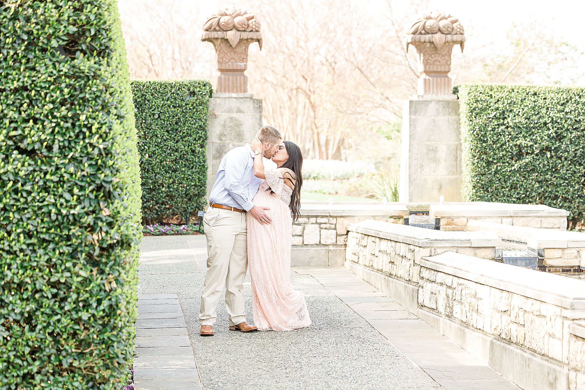 parents kiss during maternity session at Dallas Arboretum