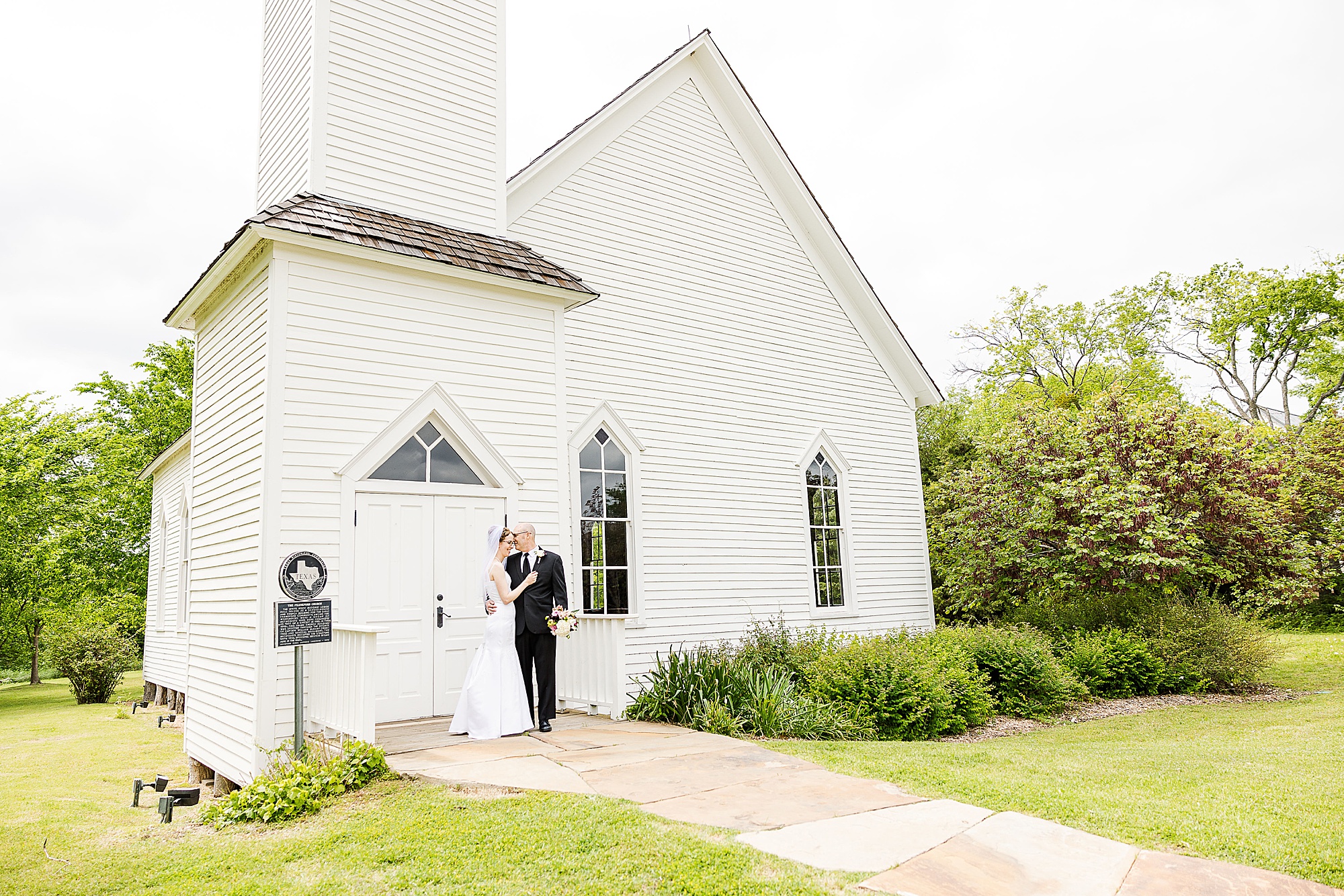newlyweds hug by white chapel in Dallas TX
