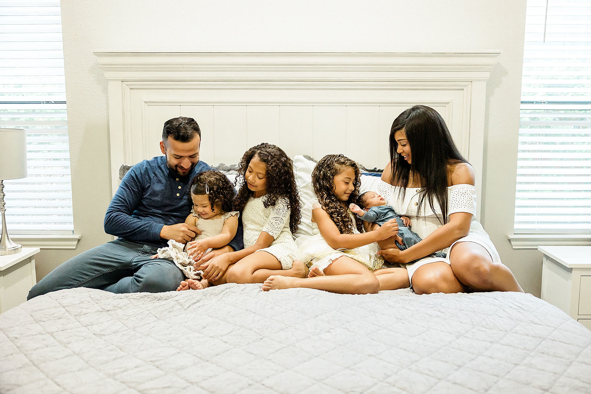parents and three daughters look at son during Dallas lifestyle newborn session