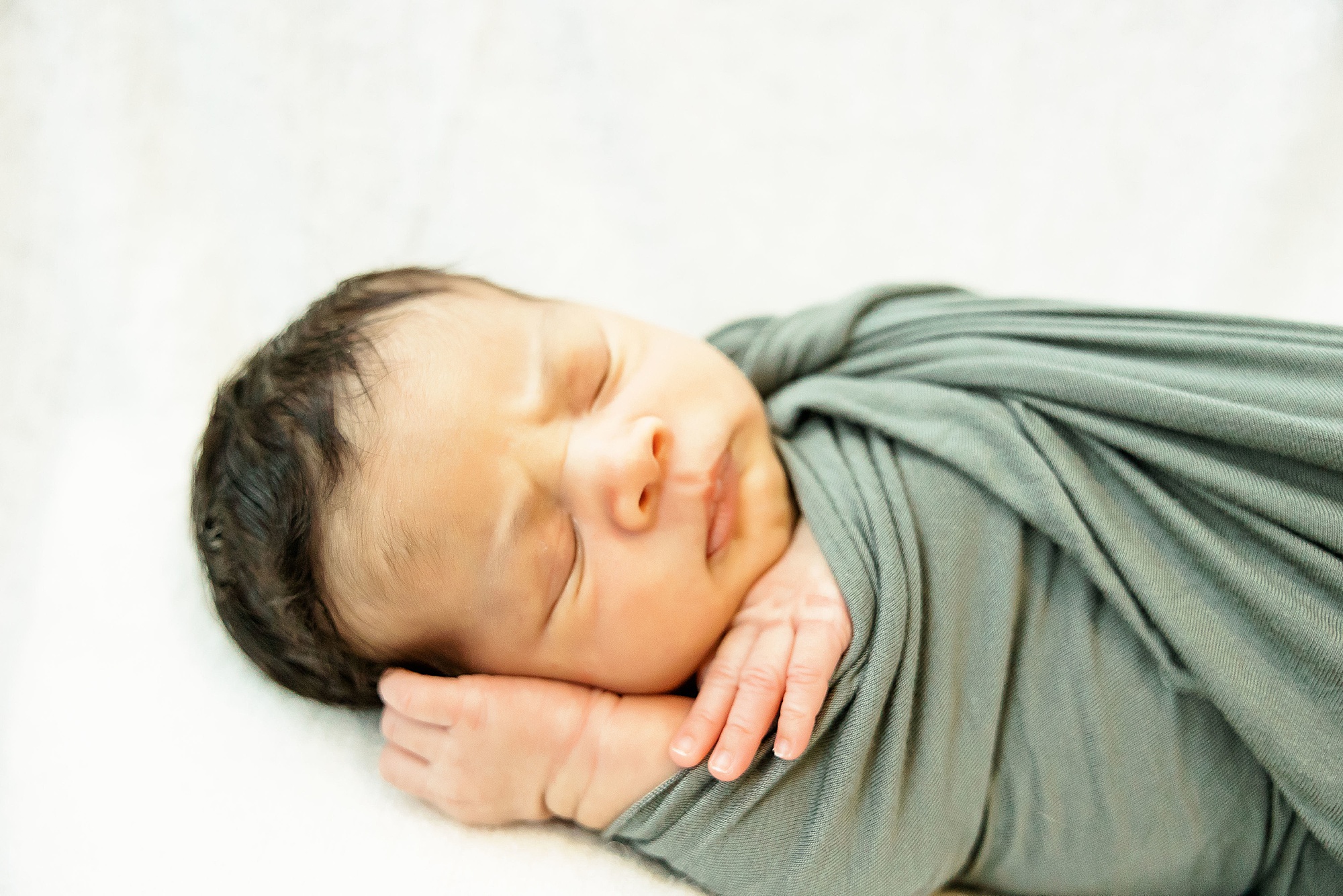 baby in sage green wrap sleeps during Dallas lifestyle newborn session