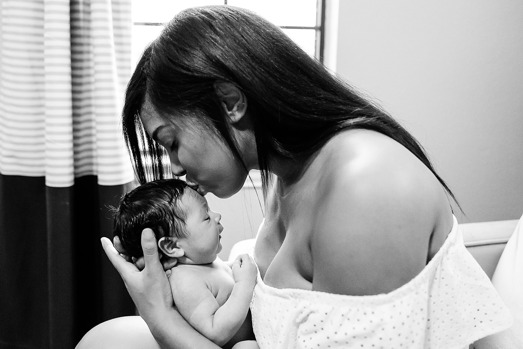 mom kisses baby boy during lifestyle newborn portraits 