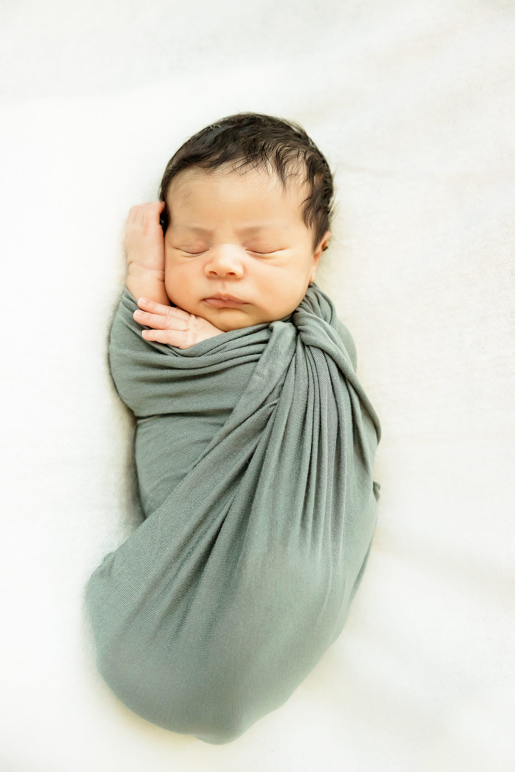baby in green wrap sleeps during newborn photos