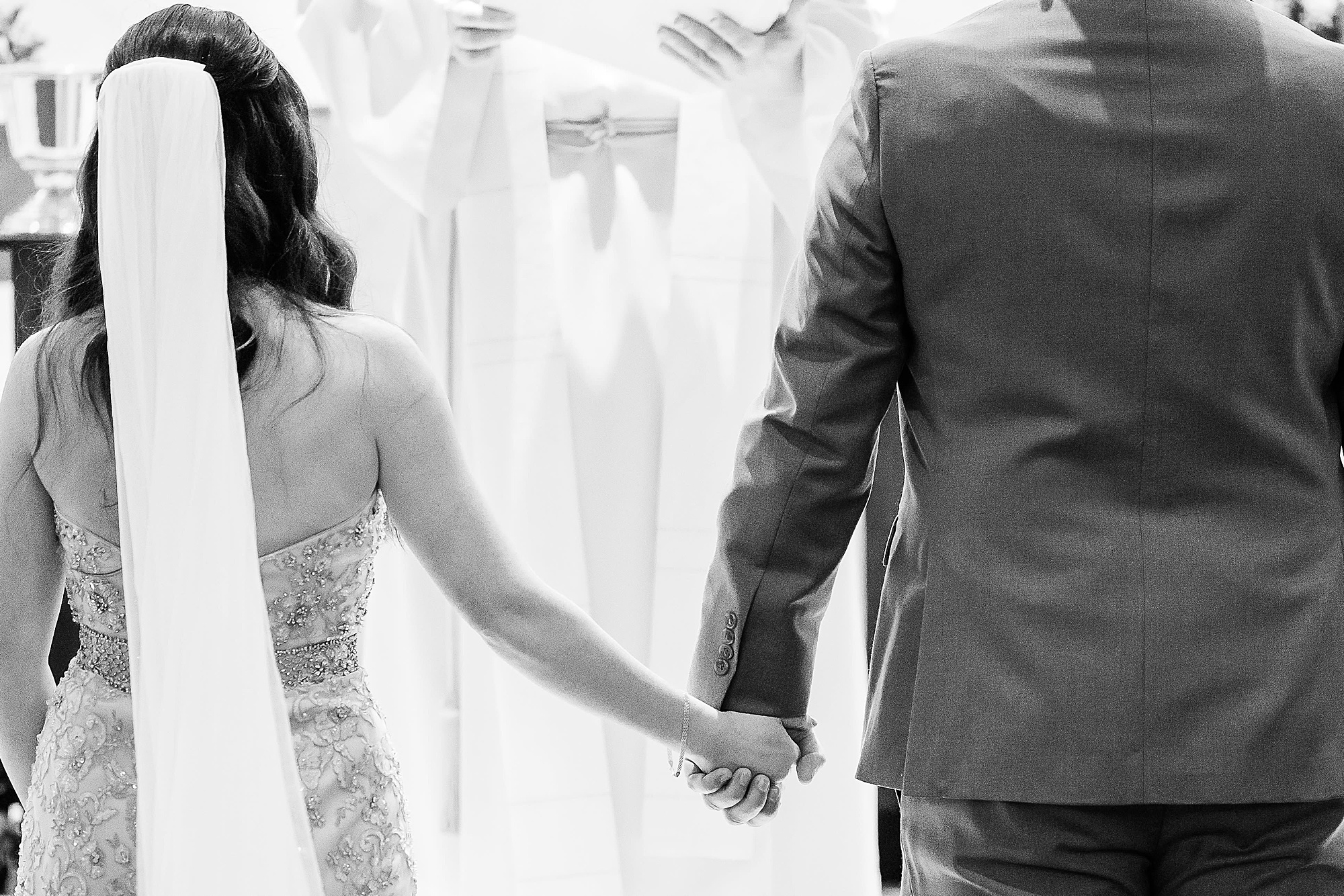 couple holds hands during church ceremony 