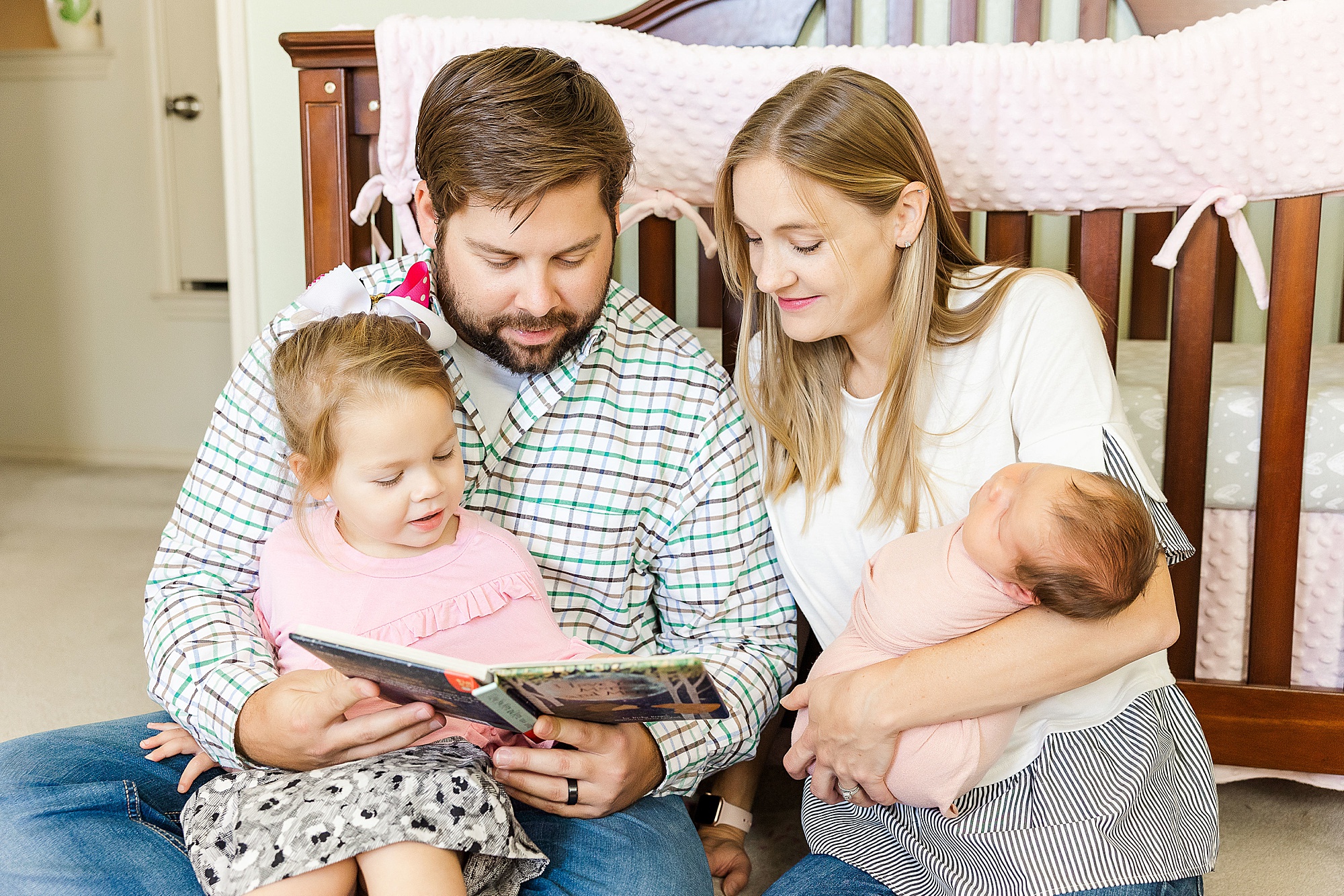 family of four sits together by crib during Krum lifestyle newborn session