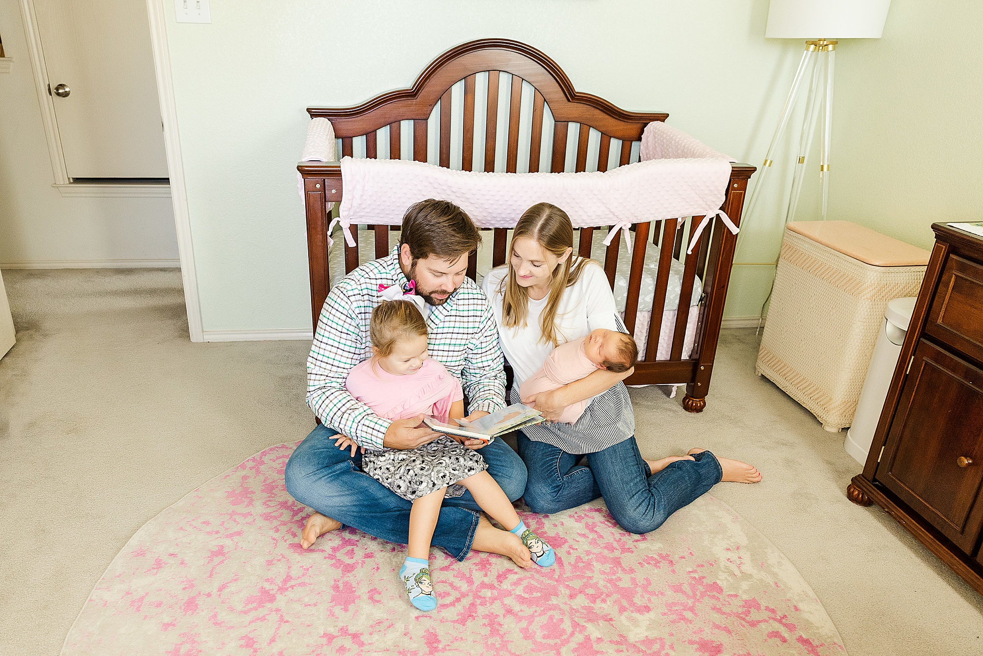 family sits on carpet in nursery during family session at home 