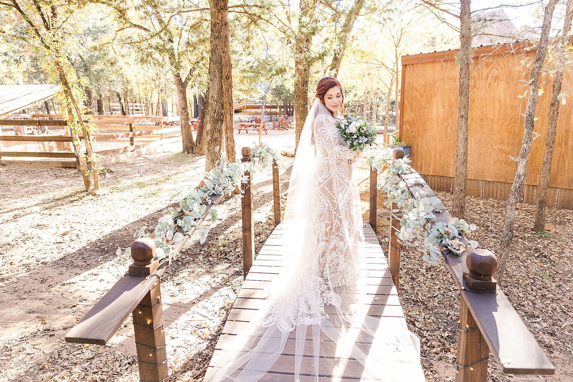 bride stands on wooden bridge at Oak Meadow Ranch