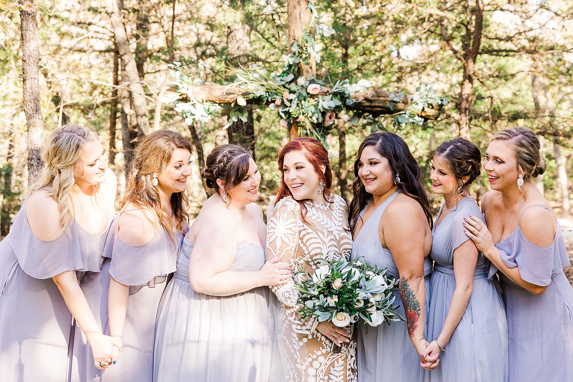 bride and bridesmaids in pastel gowns smile together 
