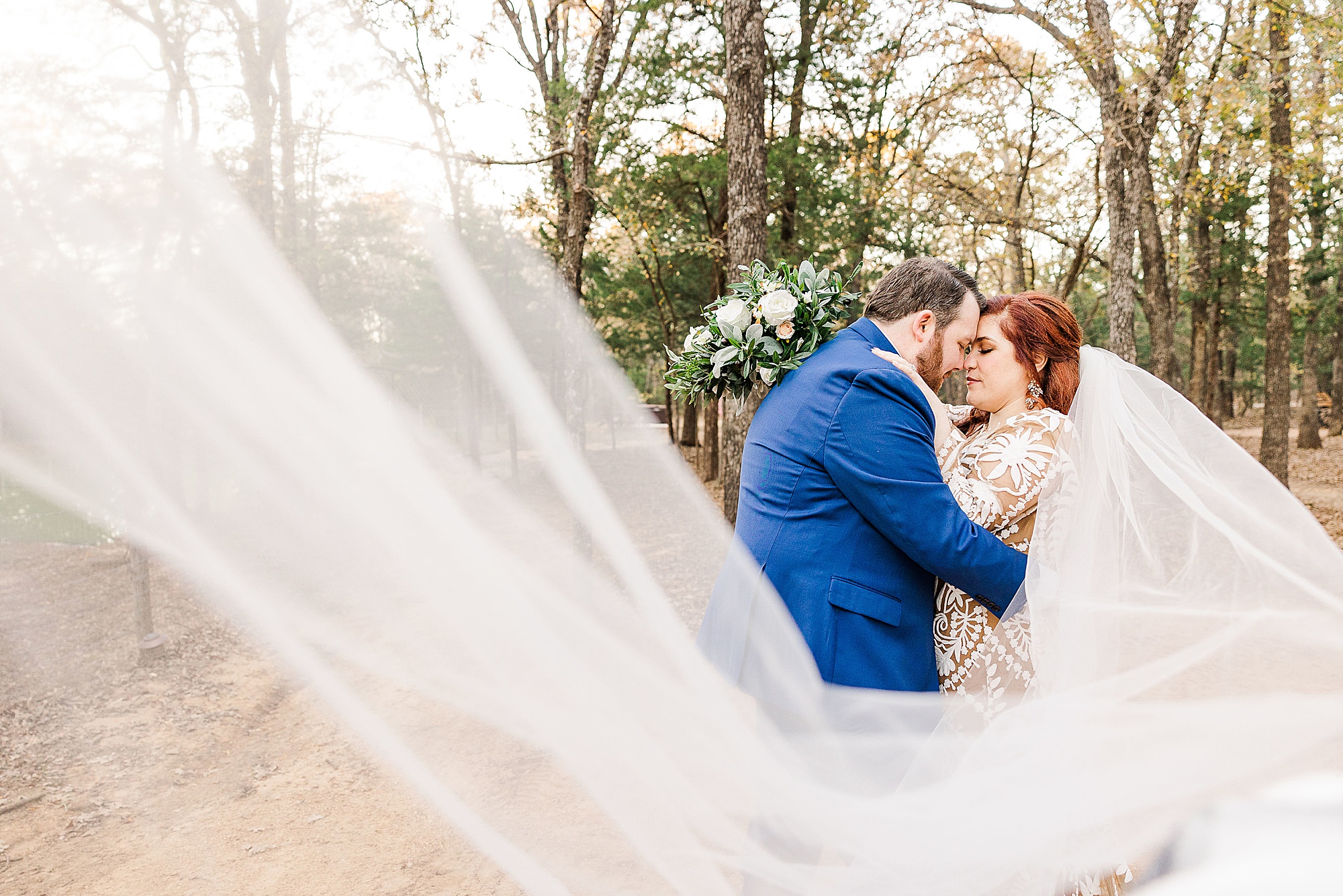 bride and groom kiss with veil draped around them