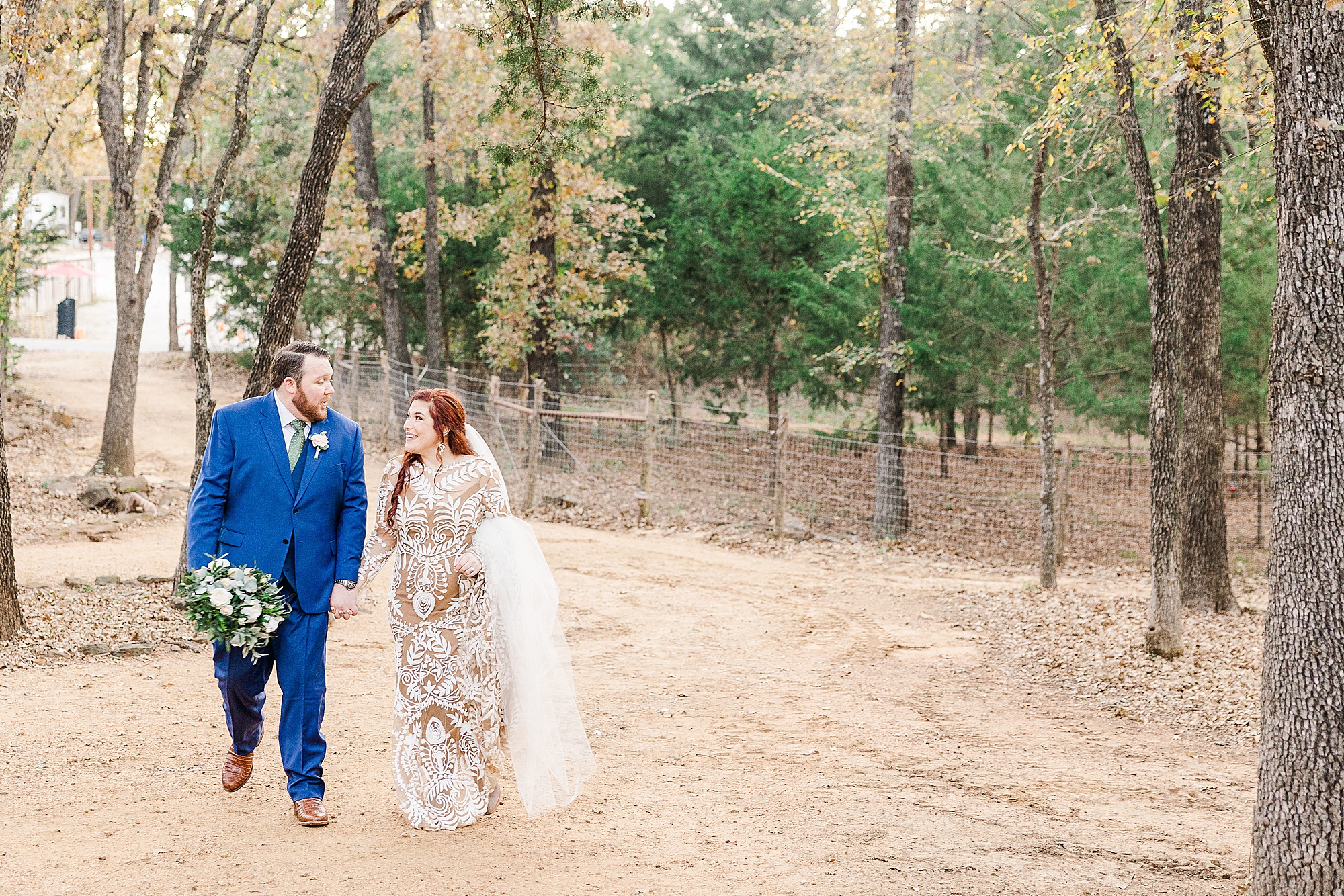 bride and groom walk through woods at Oak Meadow Ranch