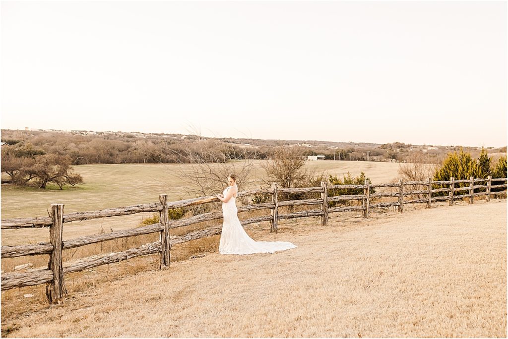 bride in white lace dress looking out over hill and field for stand-alone bridal session